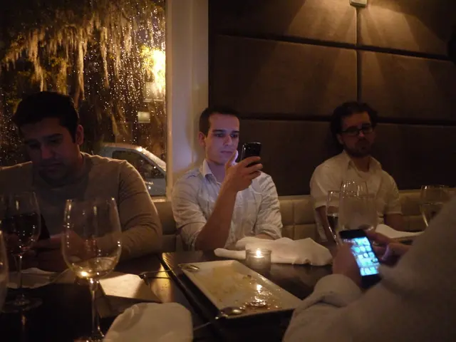 It seems to be inside a restaurant. There are men sat on sofa in front of table which has plate...